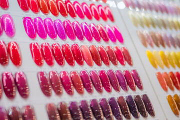 Close up: many colorful palletes of gel nail polishes on counter of make up store, manicure salon, exhibition. Fashion, makeup, care, cosmetic, beauty and glamour concept