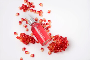 Composition with natural cosmetic oil and pomegranate on light background. 