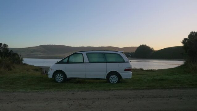 A campervan set up by a lake in the early morning, in New Zealand
