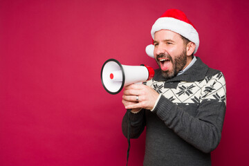 Cheerful man screaming a christmas message with a megaphone