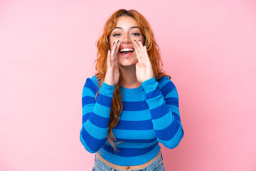 Young caucasian woman isolated on pink background shouting and announcing something