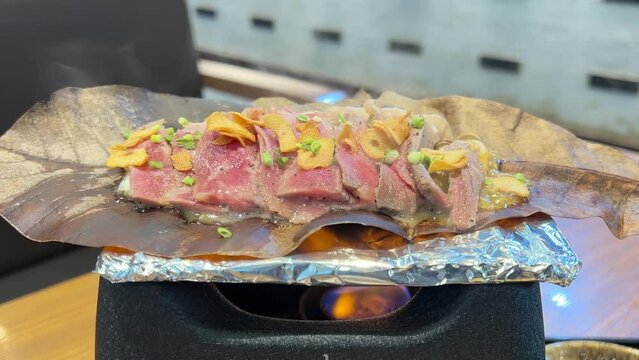 Takayama gyu hoba yaki(Grilling beef and mushroom on hoba leaf and some smoke rising over.).