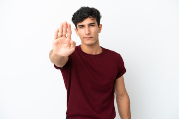 Young Argentinian man isolated on white background making stop gesture