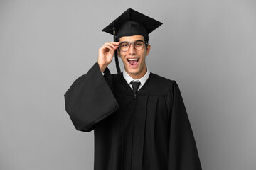 Young Argentinian university graduate isolated on grey background with glasses and surprised