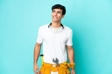 Young electrician Argentinian man isolated on blue background thinking an idea while looking up