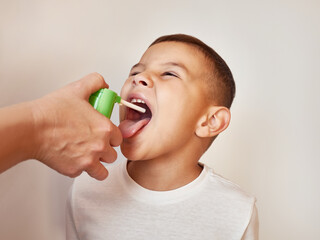 Medicine is sprayed into a sore throat of a little boy. Throat treatment.