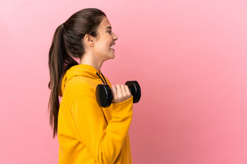 Young sport girl making weightlifting over isolated pink background laughing in lateral position