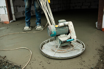 Construction worker using machine polishing surface floor smoothing and finishing hardener or epoxy concrete in the factory.