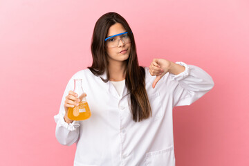 Young scientific girl over isolated pink background showing thumb down with negative expression