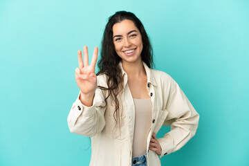Young caucasian woman isolated on blue background happy and counting three with fingers