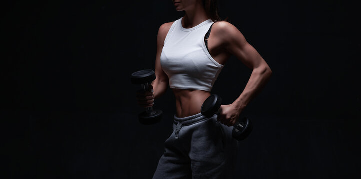 Athletic fitness woman posing in the studio on a dark background. Photo of an attractive woman in fashionable sportswear. Sports and healthy lifestyle © andy_gin