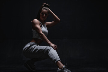 Athletic fitness woman posing in the studio on a dark background. Photo of an attractive woman in fashionable sportswear. Sports and healthy lifestyle