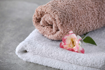 Soft towels with flower on grey table, closeup