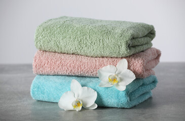 Stacked soft colorful towels with flowers on grey table