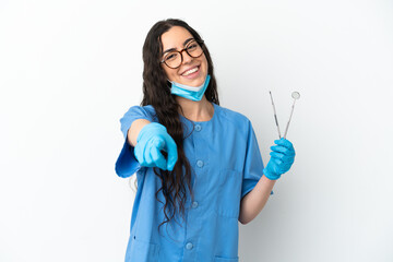 Young woman dentist holding tools isolated on white background pointing front with happy expression