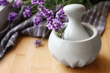 Mortar with fresh lavender flowers and pestle on wooden table, closeup. Space for text