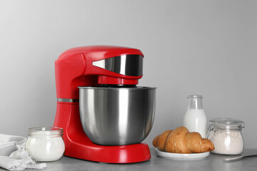 Modern red stand mixer, croissant and ingredients on gray marble table