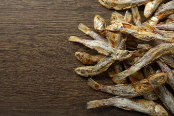 Delicious dried anchovies on wooden table, closeup. Space for text