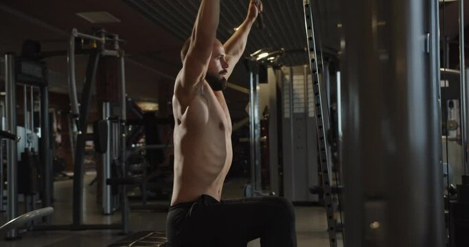 A male athlete pumps up his chest muscles on a simulator