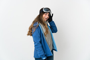Skier girl with snowboarding glasses isolated on white background listening to something by putting hand on the ear