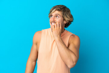 Handsome blonde man isolated on blue background is a little bit nervous
