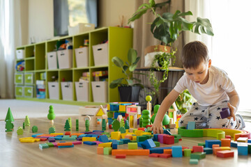 Funny baby boy playing multicolored arch Montessori wooden material structure building closeup