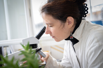 Chercheuse regardant dans un microscope dans son laboratoire de recherche