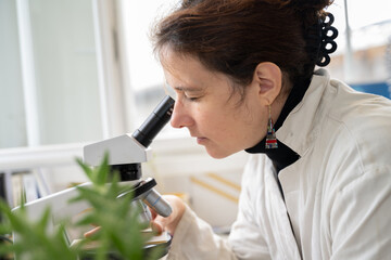 Femme regardant dans un microscope pour des recherches scientifiques