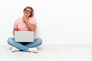 Young caucasian man sitting on the floor with his laptop isolated on white background happy and smiling