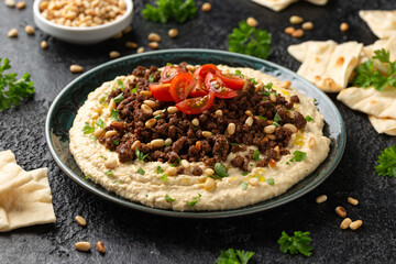 Hummus with spiced ground beef, olive oil, tomatoes and toasted pine nuts