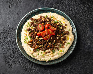 Hummus with spiced ground beef, olive oil, tomatoes and toasted pine nuts