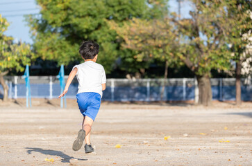 学校の校庭を走っている小学生の男の子