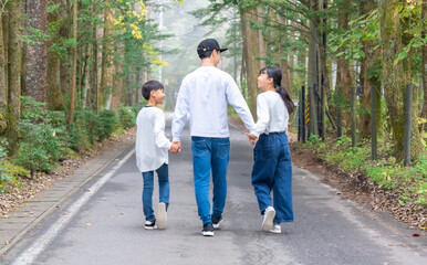 Obraz premium 手をつないで歩いている親子コーデの3人家族