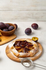 Close up of plum autumn pie on wooden board food fruits copy space
