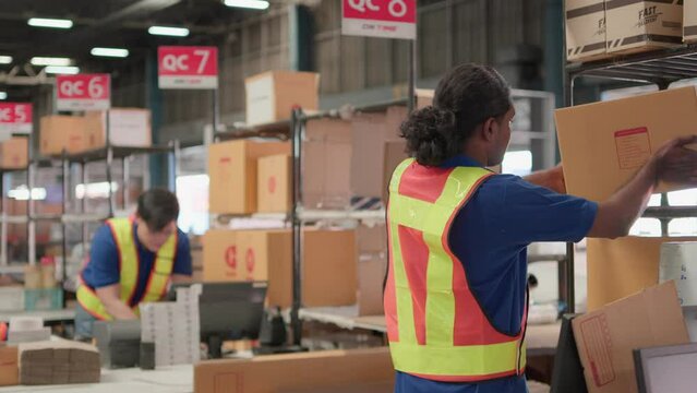 Two asian warehouse worker working checking package products in warehouse, logistic. While staff used laser barcode scanner on cardboard box, distribution center, placement in storage for shipping.