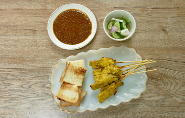 grilled pork satay couple bread dipping with sweet peanut sauce and pickled vegetable  Indonesian food on plate