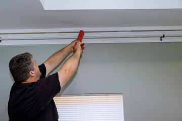 An acrylic sealant is injected into seam between cornice and ceiling using syringe used by...