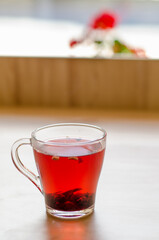 Red berry tea in a transparent cup on the background of a wooden table in a cafe