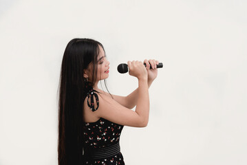 A Filipina singer poses side view for the camera while holding a wireless microphone. Studio shot isolated on a white background.