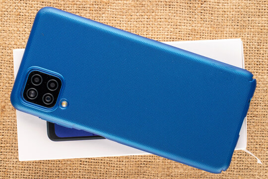 One smartphone with paper packaging on jute cloth, macro, top view.