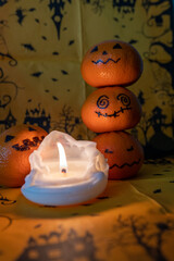 3 übereinander gestapelte Clementine gruselig bemalt als Deko zu Halloween.