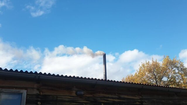 smoke from a chimney against the sky, heating of a cottage with coal, environmental pollution and energy crisis.