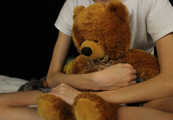 the child is sitting and holding a soft bear