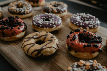 conjunto de donuts de diferentes colores con chocolate y azúcar encima de una tabla de madera