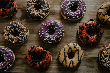 Obraz na płótnie Canvas conjunto de donuts de diferentes colores con chocolate y azúcar encima de una tabla de madera