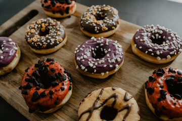 conjunto de donuts de diferentes colores con chocolate y azúcar encima de una tabla de madera