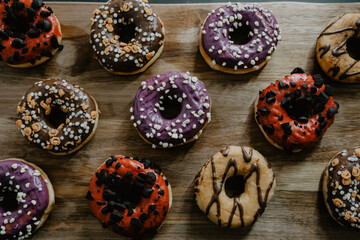 Obraz na płótnie Canvas conjunto de donuts de diferentes colores con chocolate y azúcar encima de una tabla de madera