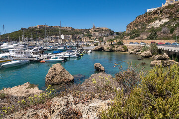 Fototapeta na wymiar Beautiful shoreline on Gozo, Malta with boats anchored. Summer weather with clear blue sky.