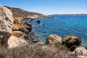 Beautiful shoreline on Gozo, Malta with boats anchored. Summer weather with clear blue sky.