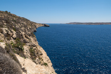 Beautiful shoreline on Gozo, Malta with boats anchored. Summer weather with clear blue sky.